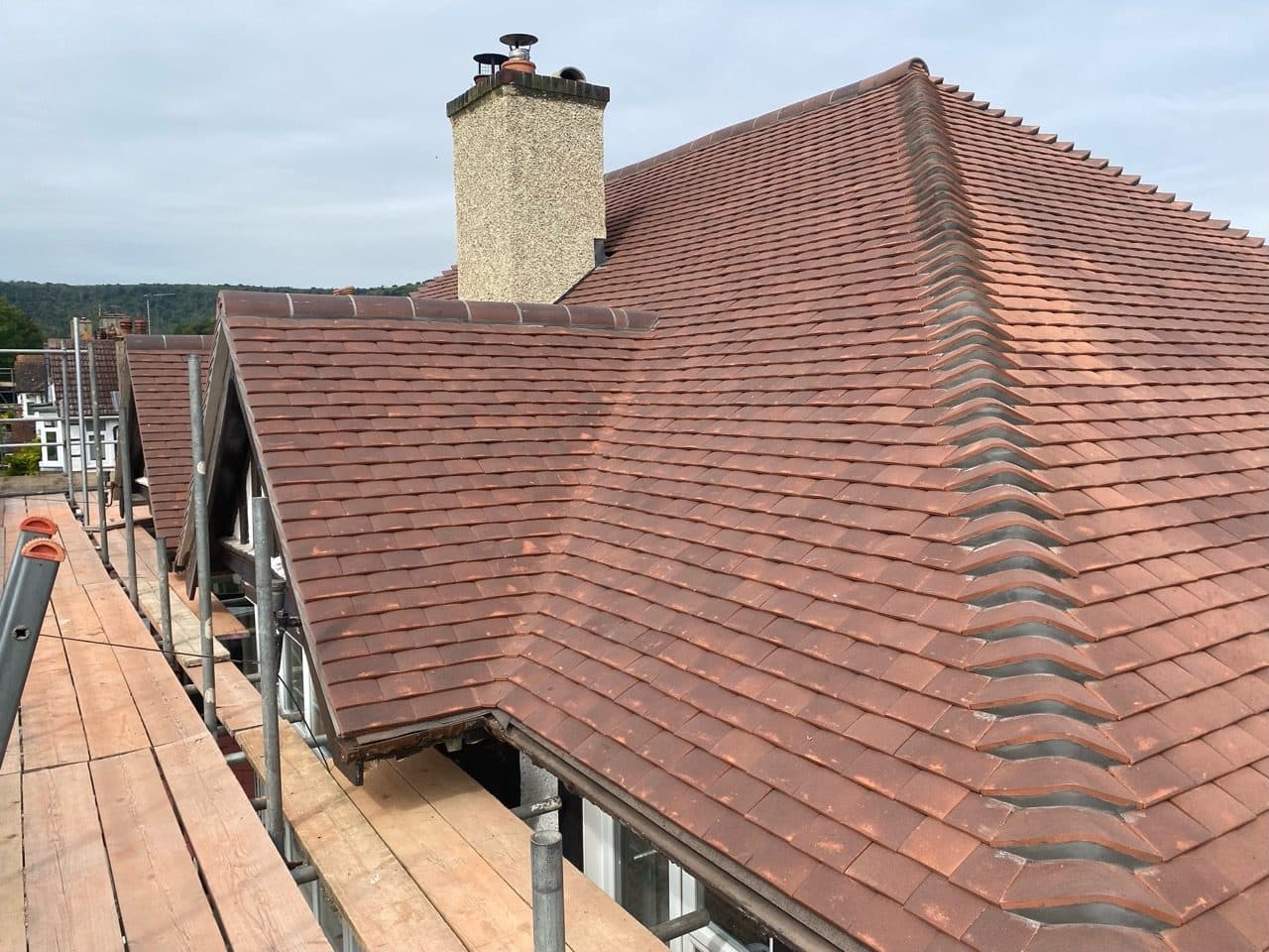 Red clay tiled roof with a chimney and scaffolding