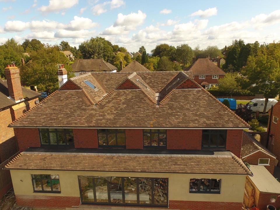 Aerial view of a large house with a red clay tiled hip-and-gable roof and rooflight